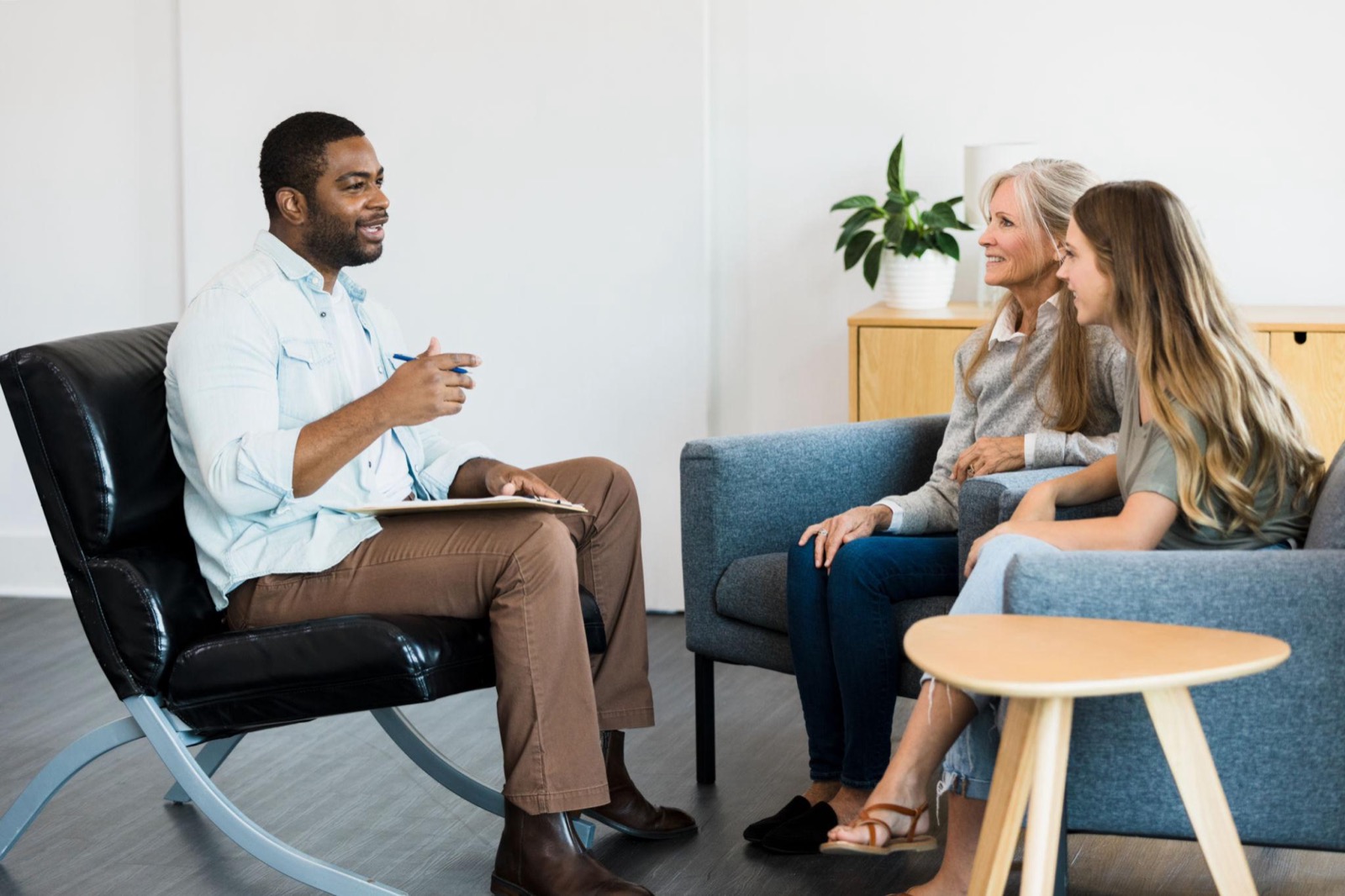 A counselor speaking with two clients in a bright, comfortable office