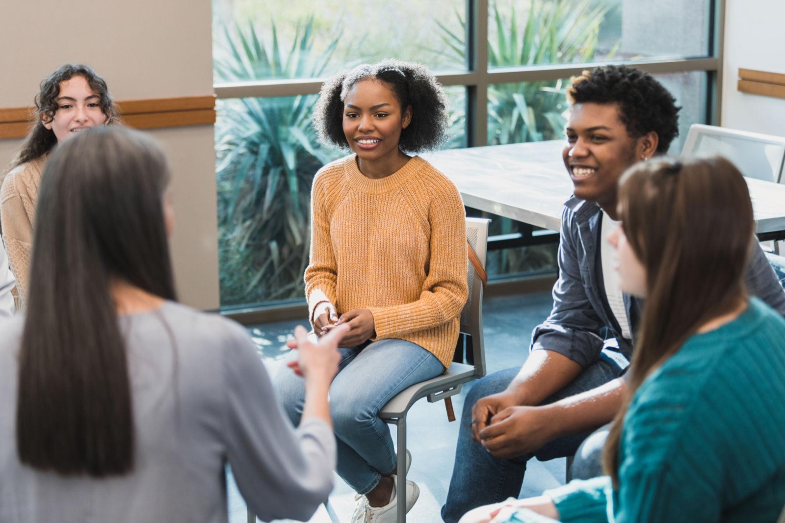 A diverse group of young people talking together in a supportive group therapy session