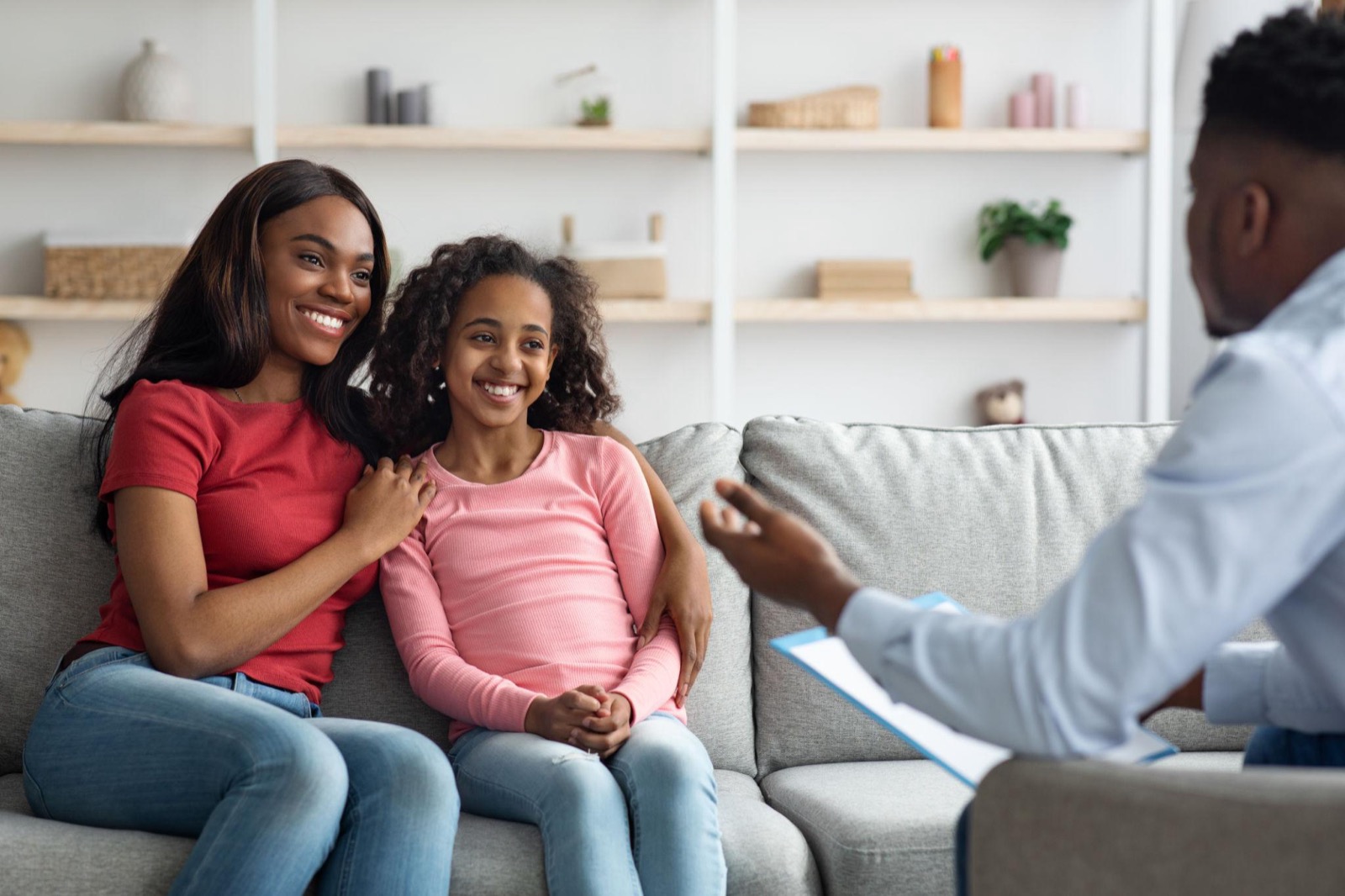 A mother and her teenage daughter smiling together during a counseling session